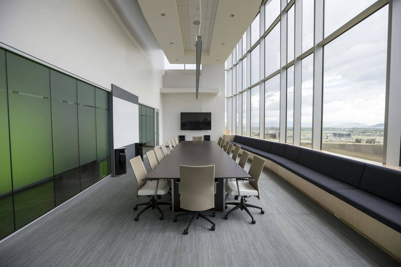 Modern glass-walled boardroom with a long table and city view
